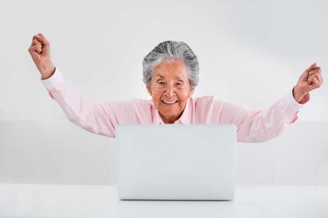 Elder woman celebrating her online success with arms up