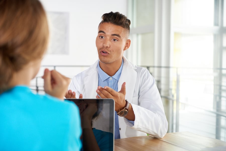 Team of doctor and nurse discussing a patient diagnosis sitting at the desk in bright modern office